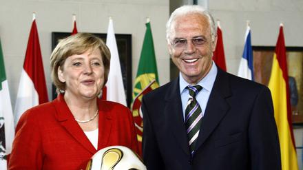 Bundeskanzlerin Angela Merkel 2006 in Berlin mit dem WM-Endspielball in der Hand neben WM-OK-Chef Franz Beckenbauer. 