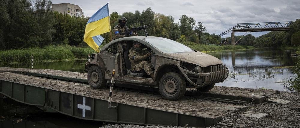 Ukrainische Fallschirmjäger fahren in einem Fahrzeug mit ukrainischer Fahne auf der Pantone-Brücke über den Fluss Siverskiy-Donets im kürzlich zurückeroberten Gebiet von Isjum.