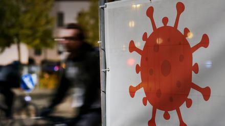Vor dem Hauptbahnhof weist ein großes Virus-Symbol auf die Corona-Teststation hin, die in Kürze öffnet, Radfahrer fahren daran vorbei.