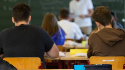 ARCHIV - 12.09.2022, Baden-Württemberg, Heitersheim: Arbeitsmaterialien liegen auf einem Tisch in einem Klassenzimmer während dahinter Schüler und ihr Lehrer zu sehen sind. (zu dpa: «Verband: Viele Schulen sind im Notbetrieb angekommen») Foto: Philipp von Ditfurth/dpa +++ dpa-Bildfunk +++