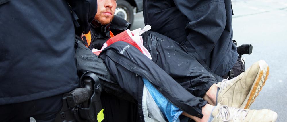 Aktivist der „letzten Generation“ wird von der Polizei weggetragen.
