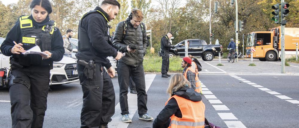 Mitglieder der Gruppe „Letzte Generation“ sitzen bei einer Blockade auf der Seestraße.