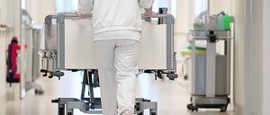 Eine Krankenpflegerin schiebt ein Krankenbett durch einen Flur.