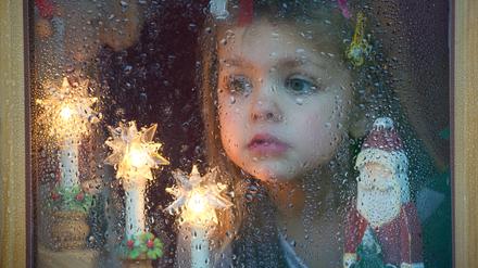Wann schneit es endlich? Ein Mädchen schaut erwartungsvoll nach draußen.
