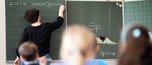 Eine Lehrerin schreibt in einer Grundschule Wörter an eine Tafel. 