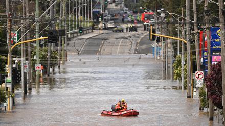 Ein Team des staatlichen Notdienstes von Australien fährt in einem Schlauchboot im Hochwasser einer überschwemmten Straße Victorias.