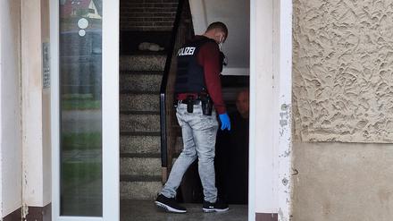 Ein Polizeibeamte geht während der Razzia in Straußfurt in einen Hauseingang.