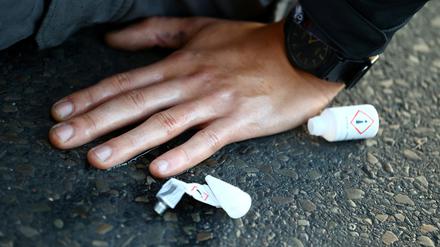 An activist of "Letzte Generation" (Last Generation) protesting for a speed limit on highways as well as for affordable public transport, glues their hand to the road at the exit of a highway in Berlin, Germany, October 11, 2022. REUTERS/Christian Mang
