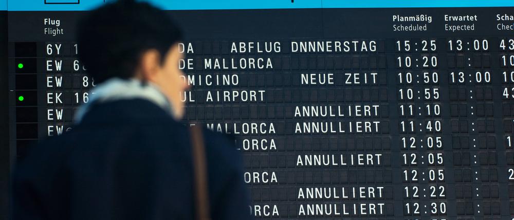 Eine Frau steht vor der Abfluginformationen am Abflugterminal des Flughafens Köln und Bonn (Archivbild)