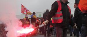 Ein streikender Arbeiter hält ein bengalisches Licht am Eingang des Öldepots von «TotalEnergies» bei Dunkirk.
