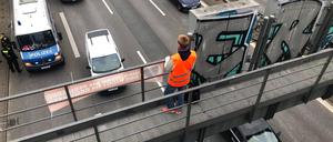 Klimaaktivist auf einer Schilderbrücke der Berliner Stadtautobahn.