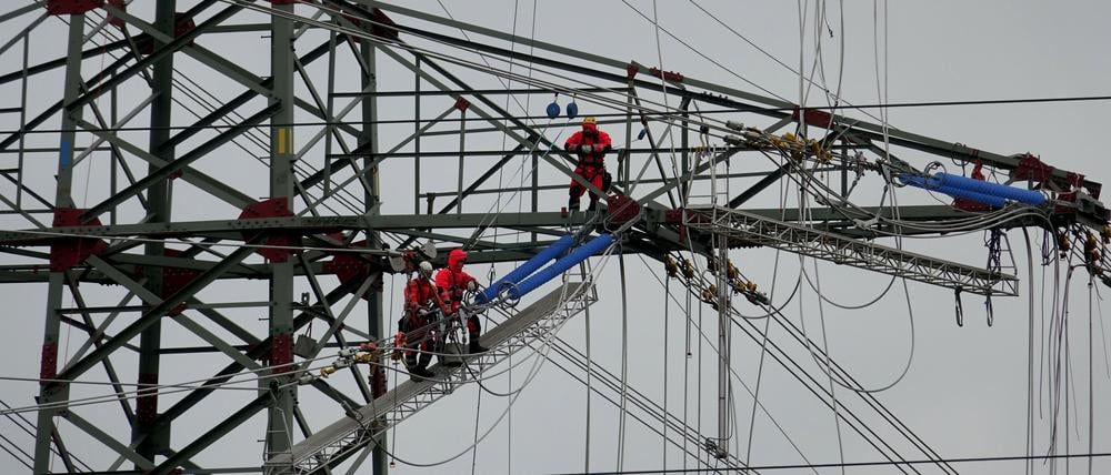 Monteure arbeiten in Brunsbüttel (Schleswig-Holstein) auf einem Strommast an neuen Leitungen. 