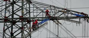 Monteure arbeiten in Brunsbüttel (Schleswig-Holstein) auf einem Strommast an neuen Leitungen. 