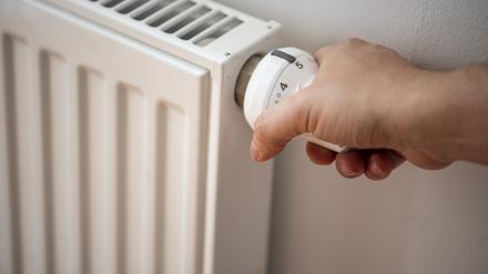 Eine Person macht eine Heizung an.