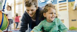 Schuhe an: Eine Erzieherin hilft einem Kita-Kind.