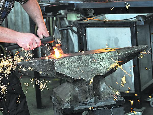   Metallbaumeister Martin Richert schmiedet mit Hammer und Amboß in der Metallwerkstatt der Stiftung Preußische Schlösser und Gärten ein Zierelement eines Metallzauns am Neuen Garten.  