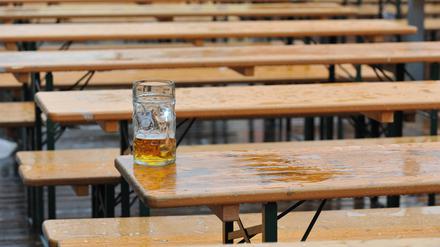 Ein Maßkrug mit Bier steht am  auf einem Biertisch in einem Biergarten vor einem Zelt auf dem Oktoberfest.