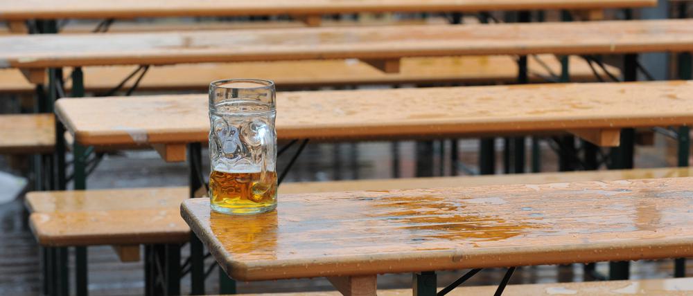 Ein Maßkrug mit Bier steht am auf einem Biertisch in einem Biergarten vor einem Zelt auf dem Oktoberfest.