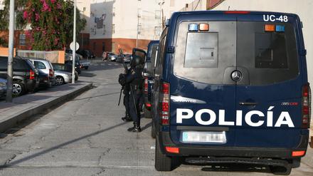 Ein Polizeiwagen und Beamte der Nationalen Polizei stehen während eines Polizeieinsatzes auf Straße.