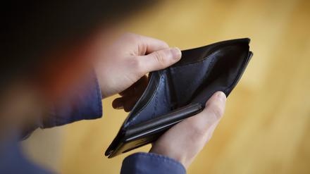 Eine Person schaut in eine leere Brieftasche. Die Zahl der überschuldeten Haushalte könnte zunehmen.