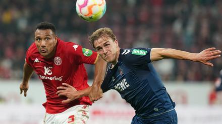 21.10.2022, Rheinland-Pfalz, Mainz: Fußball: Bundesliga, FSV Mainz 05 - 1. FC Köln, 11. Spieltag, Mewa Arena. Der Kölner Timo Hubers (r) und der Mainzer Karim Onisiwo kämpfen um den Ball. Foto: Thomas Frey/dpa - WICHTIGER HINWEIS: Gemäß den Vorgaben der DFL Deutsche Fußball Liga bzw. des DFB Deutscher Fußball-Bund ist es untersagt, in dem Stadion und/oder vom Spiel angefertigte Fotoaufnahmen in Form von Sequenzbildern und/oder videoähnlichen Fotostrecken zu verwerten bzw. verwerten zu lassen. +++ dpa-Bildfunk +++