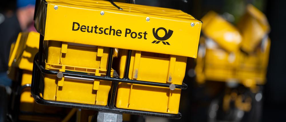 Ein Fahrrad von der Deutschen Post steht an einer Straße. 
