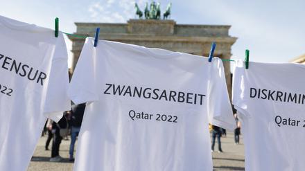 23.10.2022, Berlin: T-Shirts, mit den Begriffen wie Pressezensur, Zwangsarbeit, Diskriminierung, Gewerkschaftsverbot und Justizwillkür, hängen bei einer Kunstaktion von Amnesty International an einer Wäscheleine vor dem Brandenburger Tor. Damit soll Kritik an der menschenrechtlichen Lage in Katar sowie an Sportswashing durch Großveranstaltungen geübt und die FIFA aufgefordert werden, Verantwortung für Menschenrechtsverletzungen im Kontext der Fußball-WM zu übernehmen. Foto: Jörg Carstensen/dpa +++ dpa-Bildfunk +++