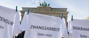 23.10.2022, Berlin: T-Shirts, mit den Begriffen wie Pressezensur, Zwangsarbeit, Diskriminierung, Gewerkschaftsverbot und Justizwillkür, hängen bei einer Kunstaktion von Amnesty International an einer Wäscheleine vor dem Brandenburger Tor. Damit soll Kritik an der menschenrechtlichen Lage in Katar sowie an Sportswashing durch Großveranstaltungen geübt und die FIFA aufgefordert werden, Verantwortung für Menschenrechtsverletzungen im Kontext der Fußball-WM zu übernehmen. Foto: Jörg Carstensen/dpa +++ dpa-Bildfunk +++