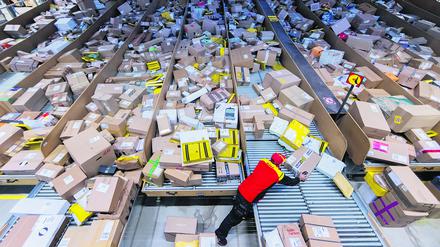 Ein Paketzusteller sortiert und räumt in einer Zustellbasis von Post DHL. 