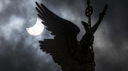 Die Sonne wird bei einer Partiellen Sonnenfinsternis teilweise vom Mond verdeckt, im Vordergrund die „Goldelse“ der Siegessäule. 