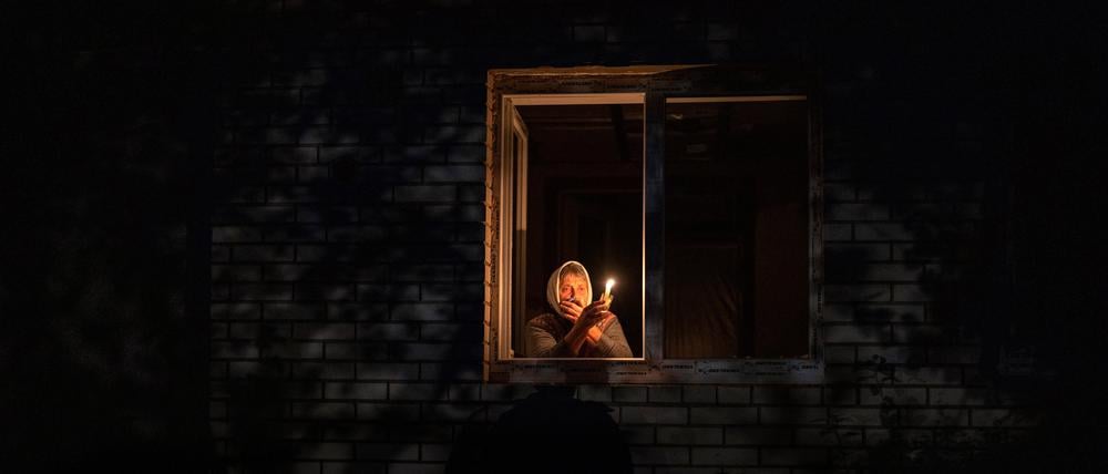 Die 70-Jährige Catherine steht während eines Stromausfalls mit einer Kerze in der Hand am Fenster.