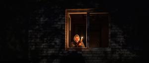 Die 70-Jährige Catherine steht während eines Stromausfalls mit einer Kerze in der Hand am Fenster.