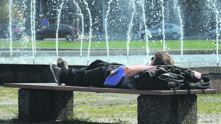 Ein junger Mann genießt auf dem Ernst-Reuter-Platz in Berlin die Sonne.