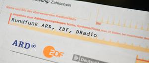 Auf einem Tisch liegt ein Anschreiben und Überweisungsträger für die Rundfunkgebühren.