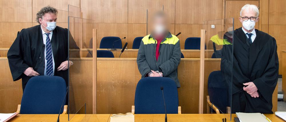 Der Angeklagte und mutmaßliche Verfasser der „NSU 2.0“-Drohschreiben steht in Handschellen hinter der Anklagebank zwischen seinen Anwälten.