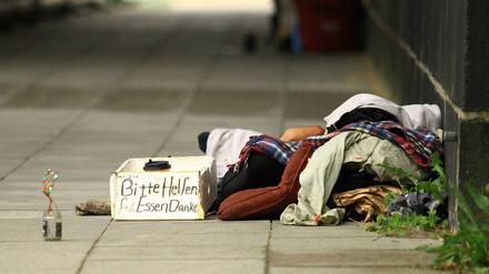 Ein Obdachloser liegt unter einer Brücke am Hamburger Dammtor. Vor ihm steht ein Kasten, auf dem ein Zettel ist, auf dem er um eine Spende für Essen bittet. Rothenbaum Hamburg *** A homeless man lies under a bridge at Hamburgs Dammtor In front of him is a box with a note asking for a donation for food Rothenbaum Hamburg 