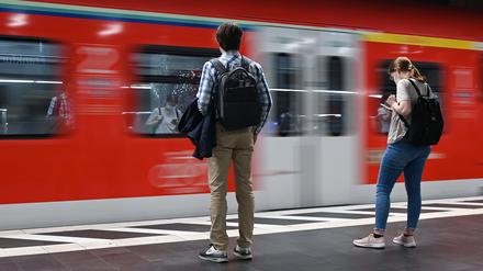 Zugreisende warten im Hauptbahnhof auf die Einfahrt einer S-Bahn.