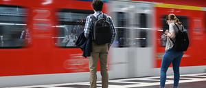 Zugreisende warten im Hauptbahnhof auf die Einfahrt einer S-Bahn.