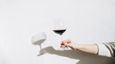 Women's hand holding a glass of red wine.