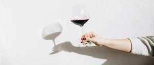 Women's hand holding a glass of red wine.