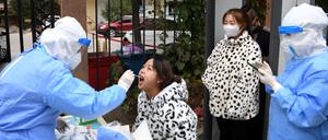 Ein medizinischer Mitarbeiter in einem Schutzanzug nimmt einen Abstrich von Einwohnern (Symbolbild).