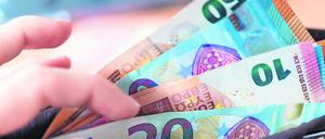 Eine Frau hält ein Portemonnaie in der Hand, in dem Geldscheine stecken.