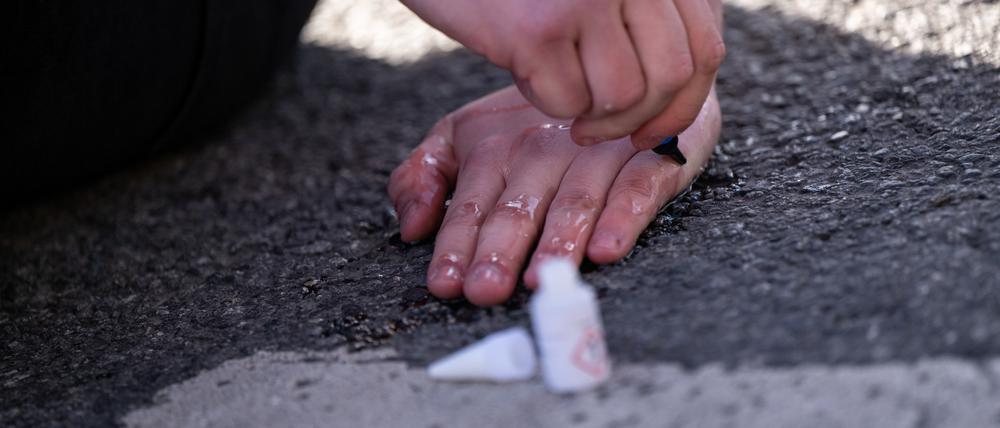 03.11.2022, Bayern, München: Ein Klimaaktivist klebt seine Hand auf die Fahrbahn am Karlsplatz in der Münchner Innenstadt Foto: Lennart Preiss/dpa +++ dpa-Bildfunk +++