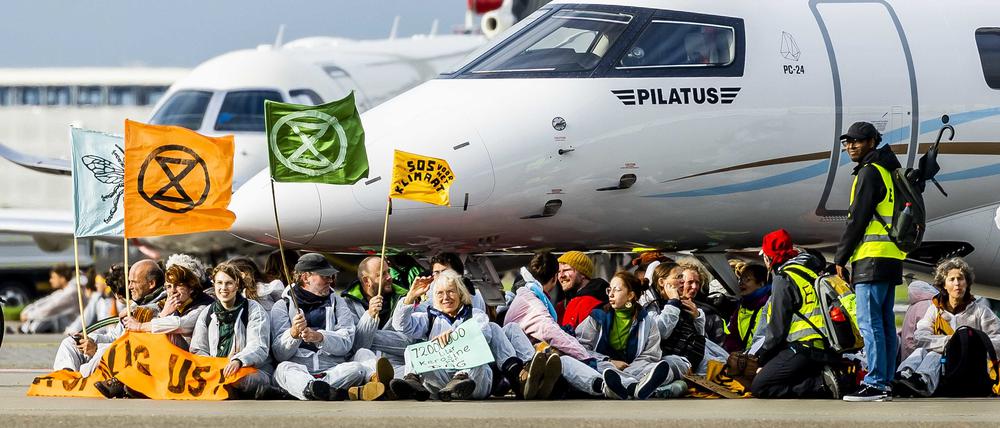 Mitglieder verschiedener Umweltvereine führen die Protestaktion „SOS für das Klima“ am Flughafen Schiphol in Amsterdam (Niederlande) durch.