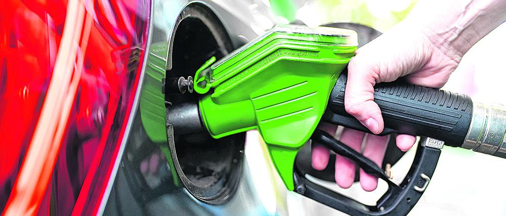 Eine Frau hält an einer Tankstelle an einer Zapfsäule eine Zapfpistole in der Hand und betankt ein Auto . (Archivbild)