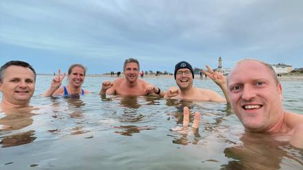 Potsdams Oberbürgermeister Mike Schubert (SPD) (Mitte) mit Ehefrau Simone (2.v.l) und Eisbademeister Gabriel  Rath (r.) aus Rostock beim Bad in der 12 Grad Celsius kalten Ostsee in Warnemünde.
