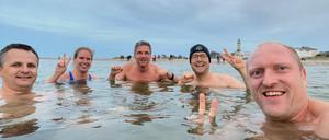 Potsdams Oberbürgermeister Mike Schubert (SPD) (Mitte) mit Ehefrau Simone (2.v.l) und Eisbademeister Gabriel  Rath (r.) aus Rostock beim Bad in der 12 Grad Celsius kalten Ostsee in Warnemünde.