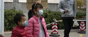 Kinder mit Masken gehen an einem Schild mit der Aufschrift „Ausgang“ an einer COVID-Teststation in Peking vorbei.