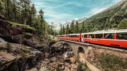 Der Bernina Express mit dem Morteratsch Gletscher im Hintergrund im Gebiet von Pontresina.