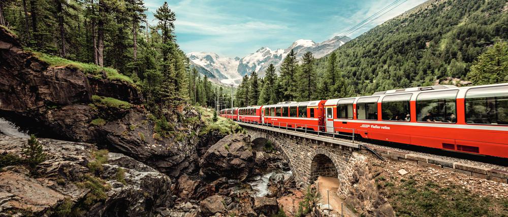 Der Bernina Express mit dem Morteratsch Gletscher im Hintergrund im Gebiet von Pontresina.